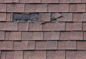 wind damage to roof-close up image of missing shingles on a brown roof