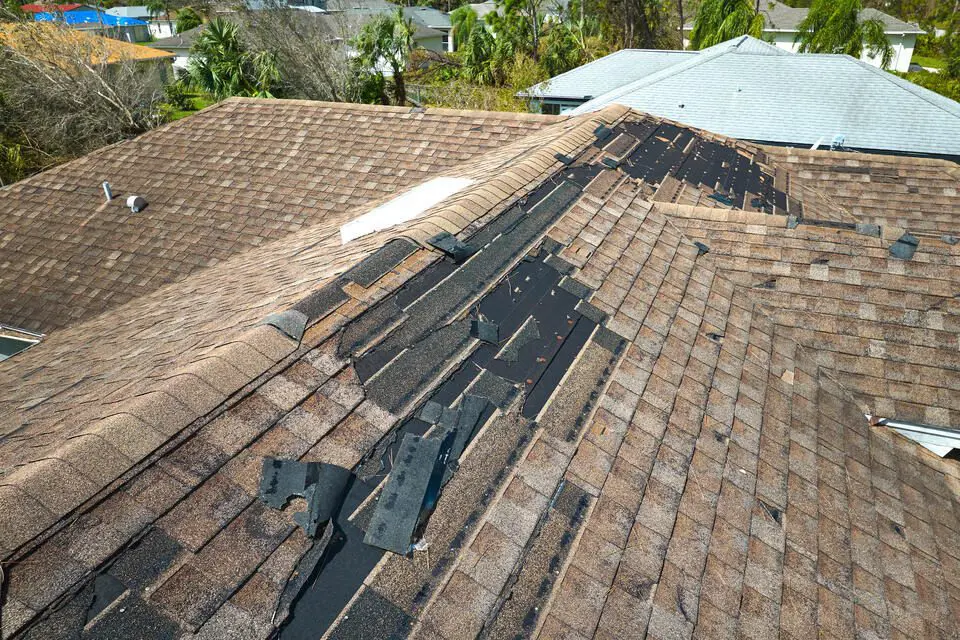 wind damage to roof-overhead view of missing shingles on a brown roof