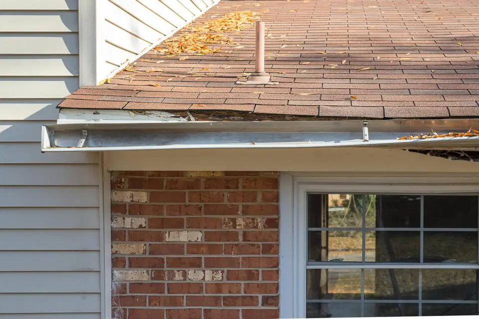 gutter repair-home with brick and siding with damaged gutter system