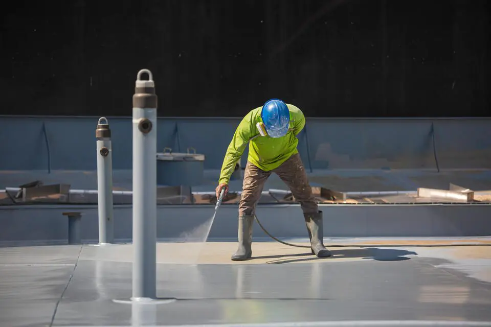 roof coatings-man spraying a roof coating onto a flat roof