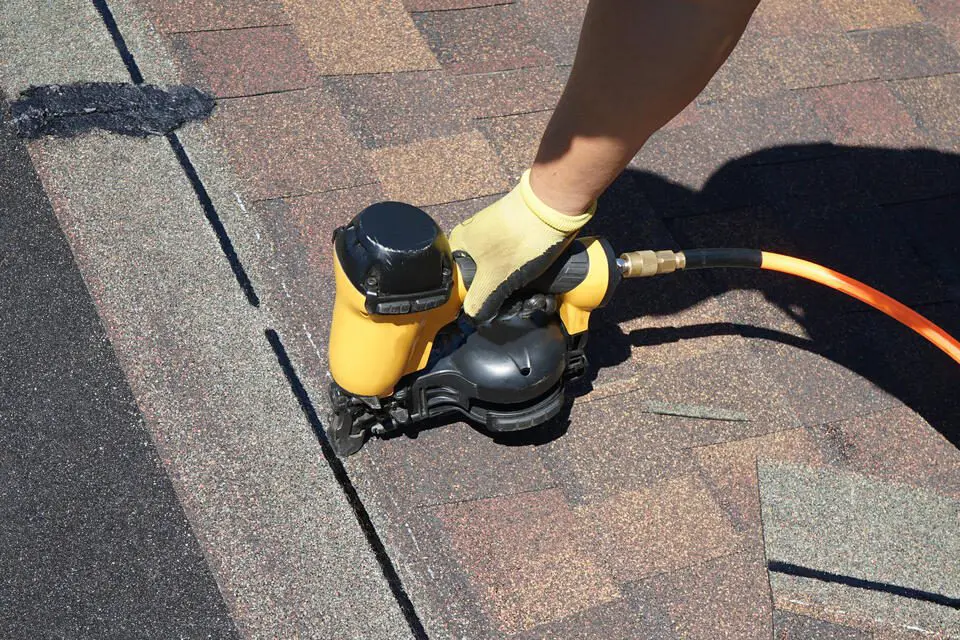 should I stay home during roof replacement-close up of roofer installing new shingles with power tools