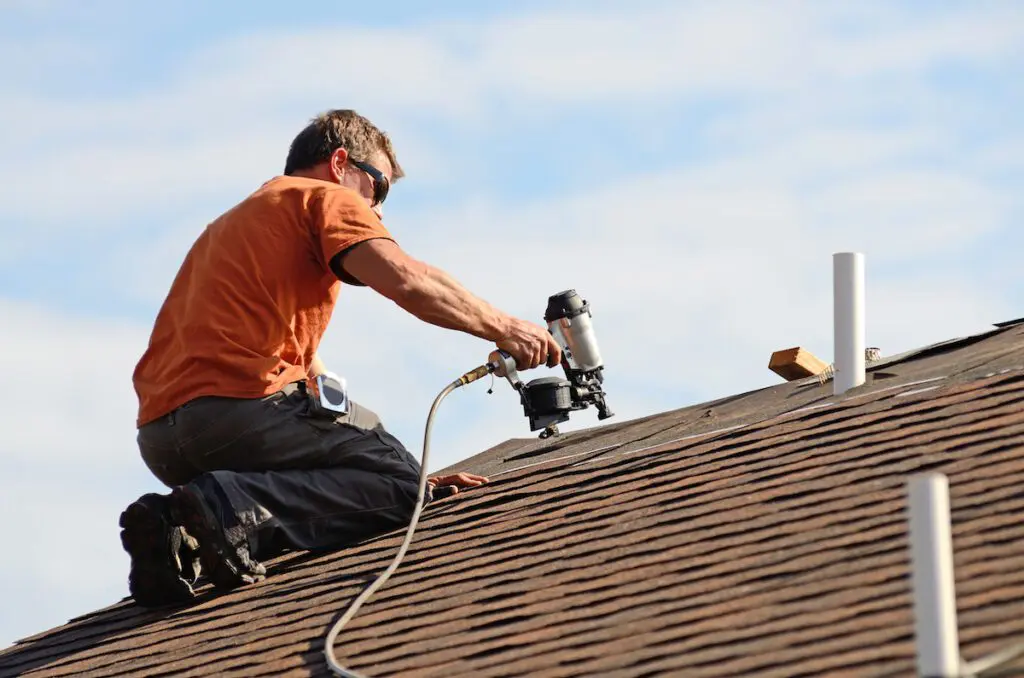 Building contractor putting the asphalt roofing on a large commercial apartment building development