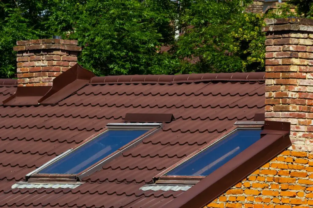 Red house roof with red brick chimney. Ceramic chimney, metal roof tiles, gutters. what is roof flashing