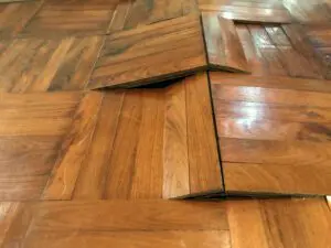 Damaged parquet floor warped and bent due to humidity and moisture