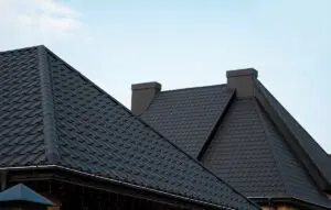 Black metal tile roof. Roof metal sheets. Modern types of roofing materials. Roof of the house, metal roof tile against the blue sky. Building