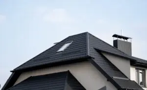 Black metal tile roof. Roof metal sheets. Modern types of roofing materials. Roof of the house, metal roof tile against the blue sky. Building