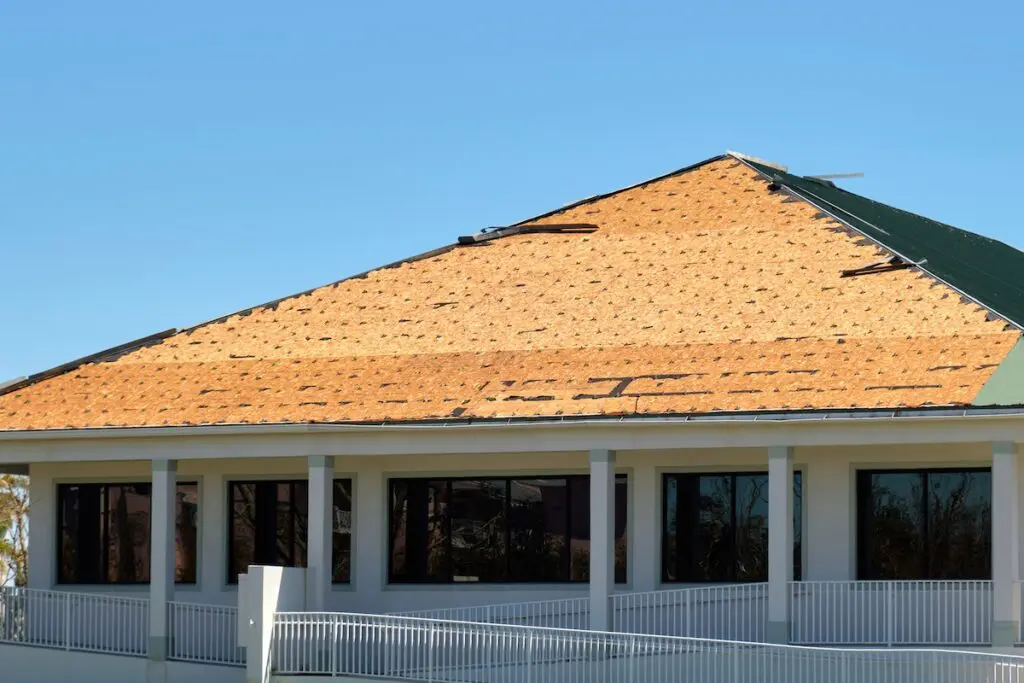 Damaged house roof with missing shingles after hurricane Ian in Florida. Consequences of natural disaster.