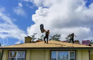 Roof workers tears off old shingles
