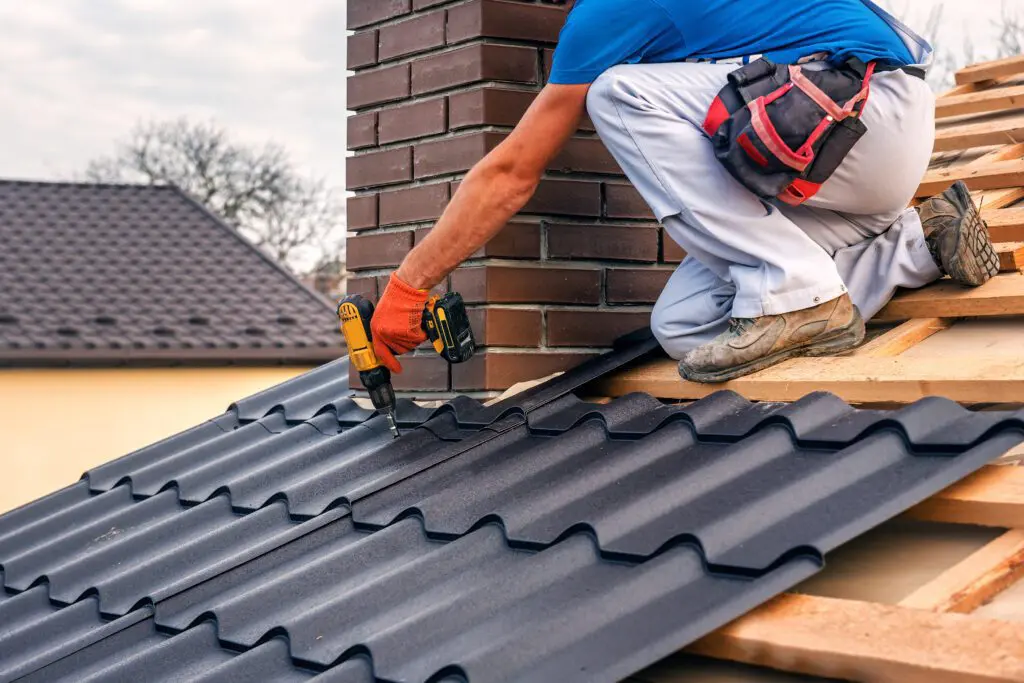 a professional master (roofer) with electric screwdriver covers repairs the roof near the chimney roof restoration vs replacement