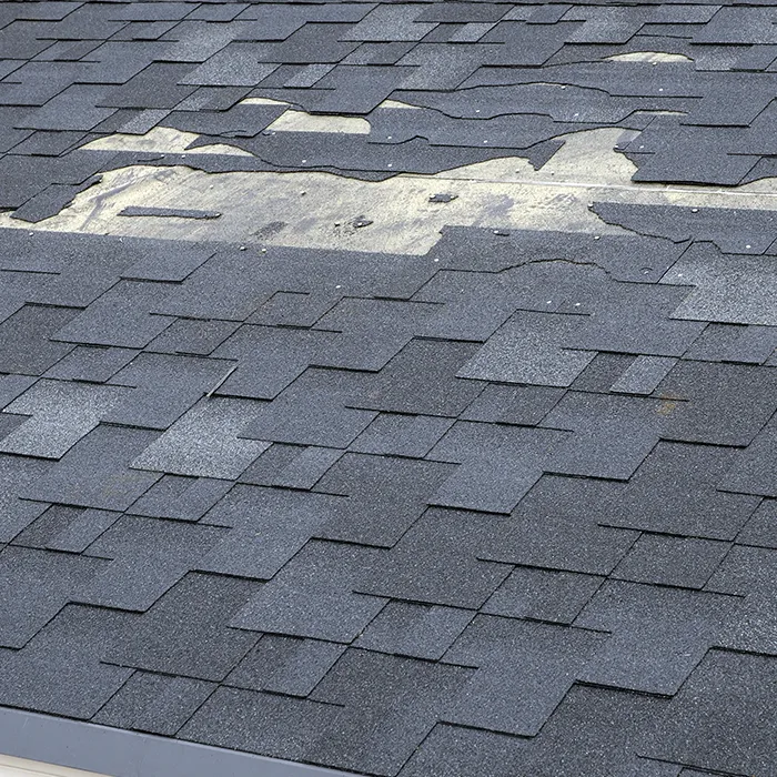 closeup of cracked and peeling shingles on roof due to storm damage