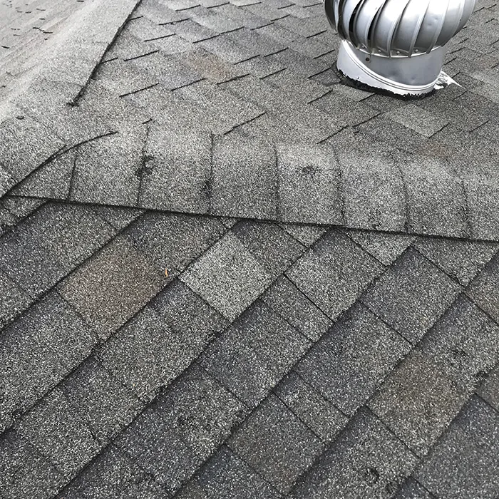 closeup of roof shingles and roof vent after storm damage