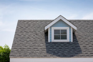 metal roof vs shingles-close up of gray architectural shingles on a blue sided house