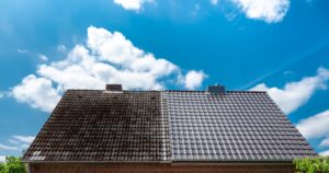 A half cleaned house roof shows the before and after effect of a roof cleaning.