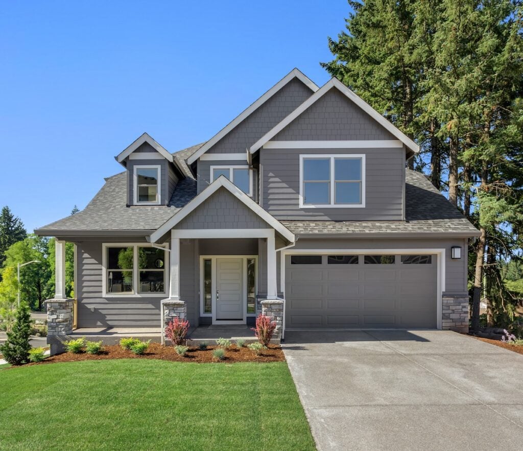 Suburban home exterior on bright sunny day, with large yard and covered porch