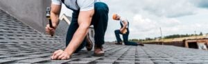 Top-Notch Mold Remediation in Dublin, OH - All Phase Roofing & Restoration panoramic shot of handyman holding hammer while repairing roof near coworker
