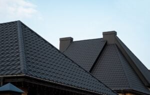 Roofing: Columbus - All Phase Roofing & Restoration Black metal tile roof. Roof metal sheets. Modern types of roofing materials. Roof of the house, metal roof tile against the blue sky. Building