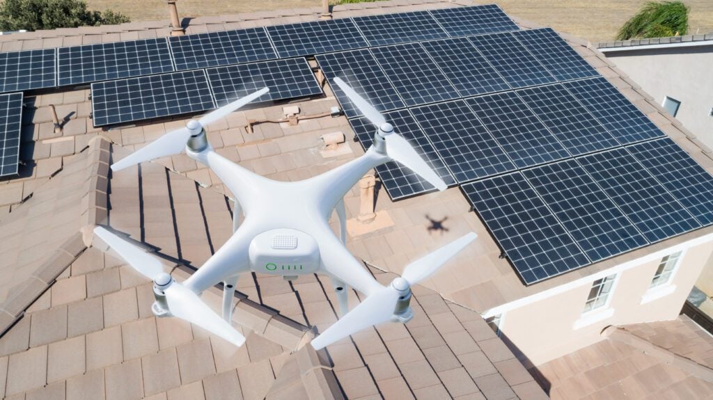 Drone Roof Inspection: What Are The Top 4 Benefits? - All Phase Roofing & Restoration UAV Drone Inspecting Solar Panels On Large House.