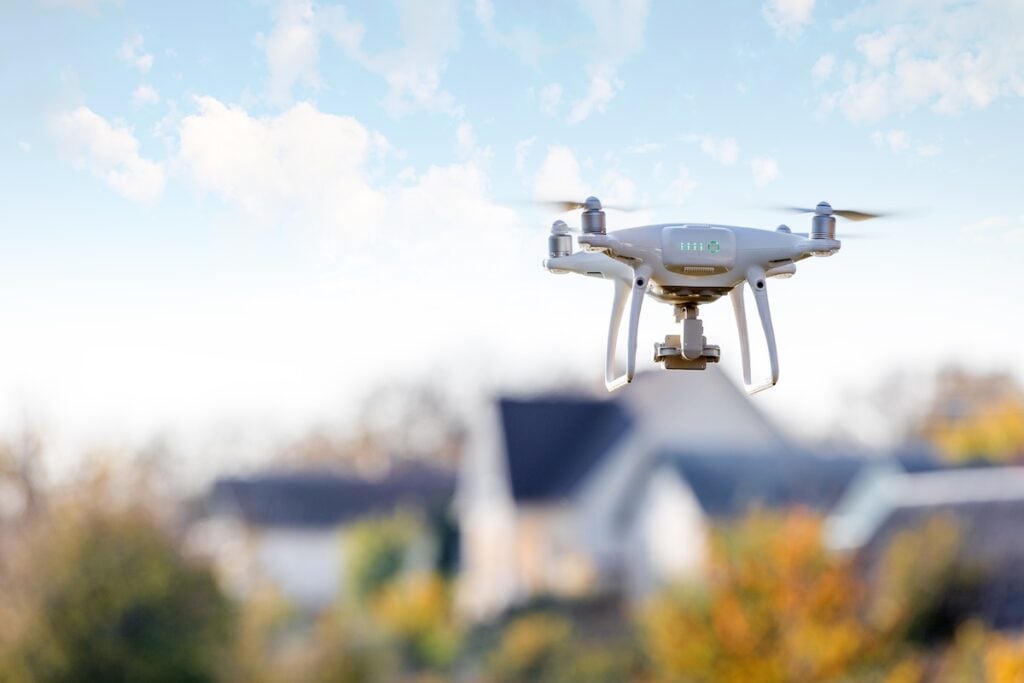 Drone Roof Inspection: What Are The Top 4 Benefits? - All Phase Roofing & Restoration drone flying front of home