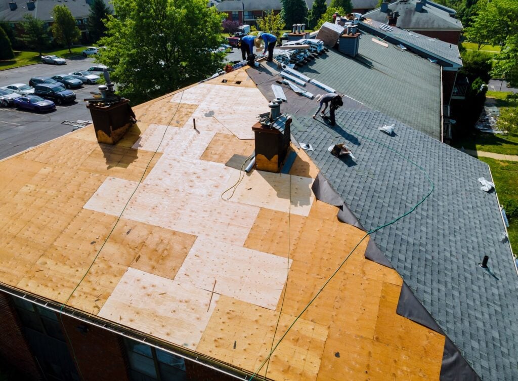 Average Cost to Tear Off and Replace Roof (2025) - All Phase Roofing & Restoration Roof repairs old roof replacement with new shingles of an apartment building